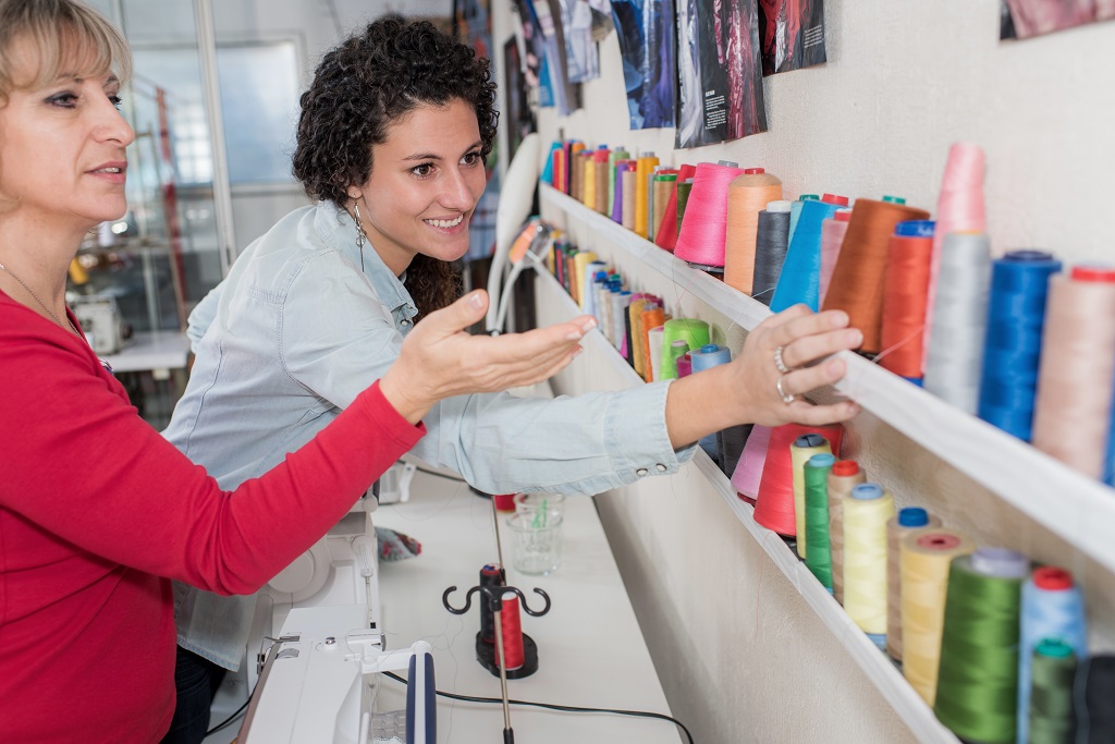 two women choosing thread reels in sewing store